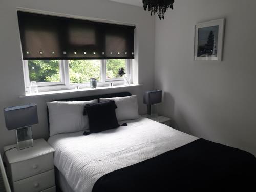 a bedroom with a black and white bed and two windows at A&S properties, no guest fees, with drive and near city centre in Wolverhampton
