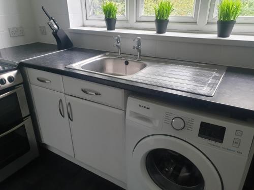 a kitchen with a sink and a washing machine at A&S properties, no guest fees, with drive and near city centre in Wolverhampton