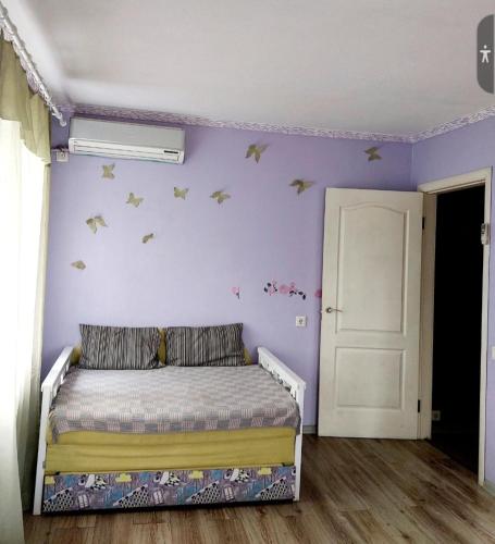 - une chambre avec un lit et un mur violet dans l'établissement Апартаменты в стиле Loft, à Nizhnedneprovsk
