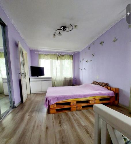 - une chambre avec des murs violets et un lit avec une couverture violette dans l'établissement Апартаменты в стиле Loft, à Nizhnedneprovsk