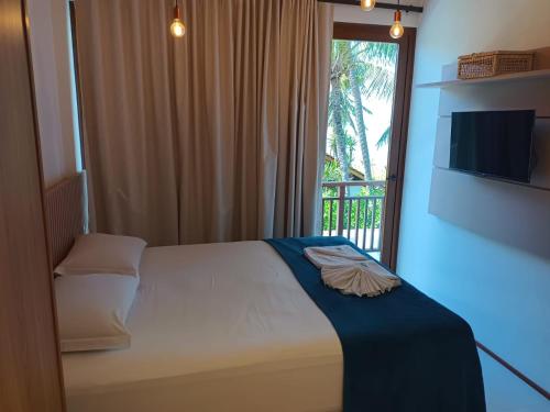a bedroom with a bed and a window with a television at Beach Premium Praia do Forte in Praia do Forte