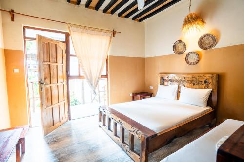 a bedroom with a bed and a large window at La Fontana Zanzibar in Kendwa