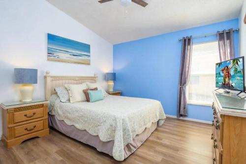 a blue bedroom with a bed and a television at Spacious Vacation Home Near Disney w/ Private Pool- Perfect for Families! in Davenport
