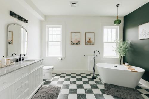 a bathroom with a white tub and a black and white checkered floor at Newly Renovated Vintage Inspired Large 4 BR Home in Mount Joy