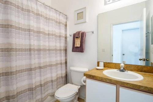 a bathroom with a sink and a toilet and a mirror at Spacious Vacation Home Near Disney w/ Private Pool- Perfect for Families! in Davenport