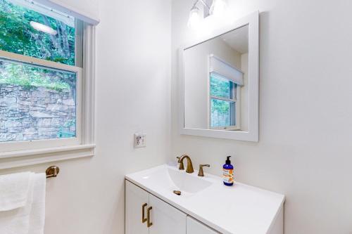 Baño blanco con lavabo y espejo en Blue Ridge Cottage, en Waynesville