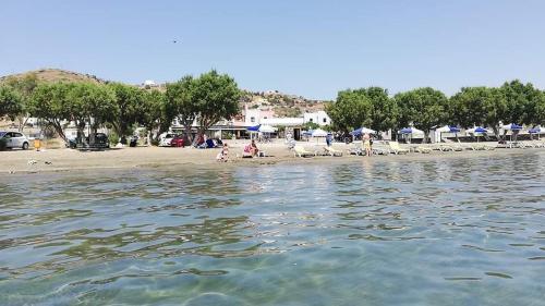 a beach with chairs and umbrellas and people on the beach at Leros Sunset Apartments in Gourna