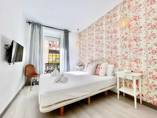 - une chambre avec un lit blanc et du papier peint floral dans l'établissement Charming Puerta del Sol Center - 6 Bedrooms, à Madrid