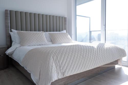 a bedroom with a white bed with a large window at Modern luxury Waterfront Condo in Mississauga