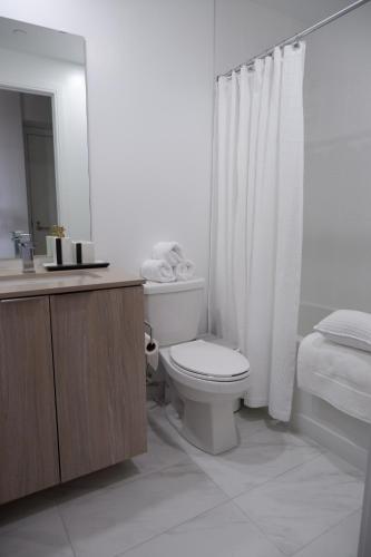 a white bathroom with a toilet and a shower at Modern luxury Waterfront Condo in Mississauga