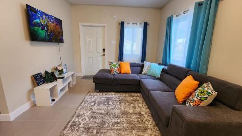 a living room with a gray couch and orange pillows at OceanAire Crest @ Oceanpointe in Lucea