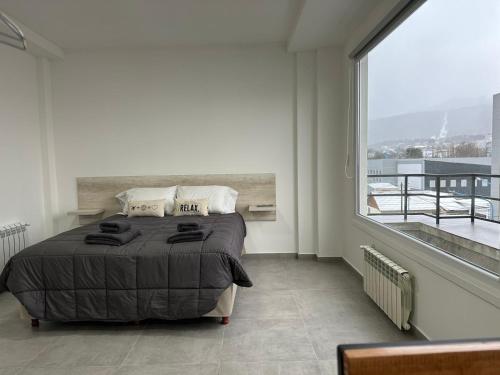 een slaapkamer met een bed en een groot raam bij Jainen Apartamentos in Ushuaia