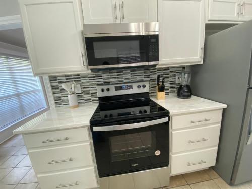 a kitchen with a stove and a microwave at Pool House in Broussard