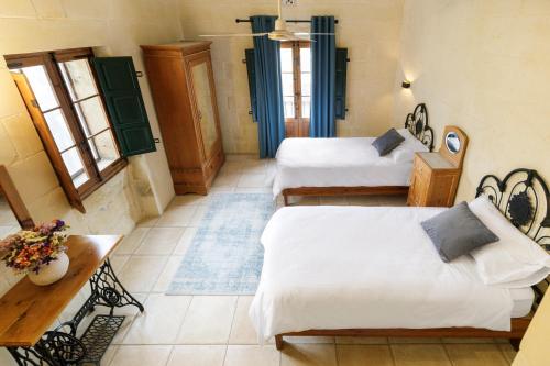a room with two beds and a table at Dar tal-Patri Farmhouse with Private Pool in Għammar