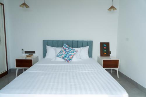 een slaapkamer met een wit bed en 2 nachtkastjes bij Four Petals Inn in Colombo