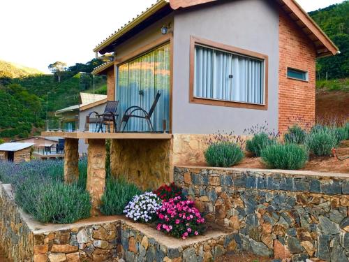 a house with a stone retaining wall and flowers at Valle Piemonte in Divisa
