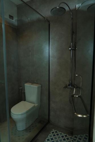 a bathroom with a toilet and a glass shower stall at Four Petals Inn in Colombo