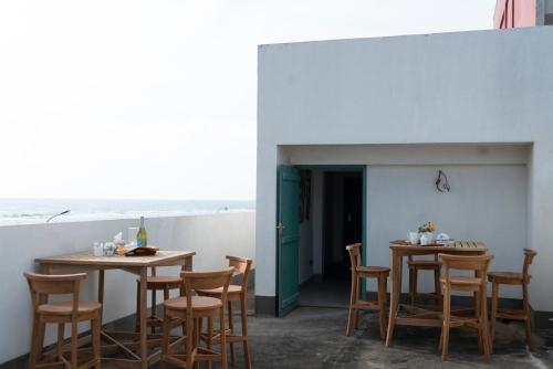 un patio con 2 mesas y sillas y el océano en Four Petals Inn, en Colombo