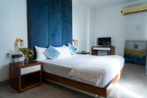 a bedroom with a white bed with a blue wall at Four Petals Inn in Colombo