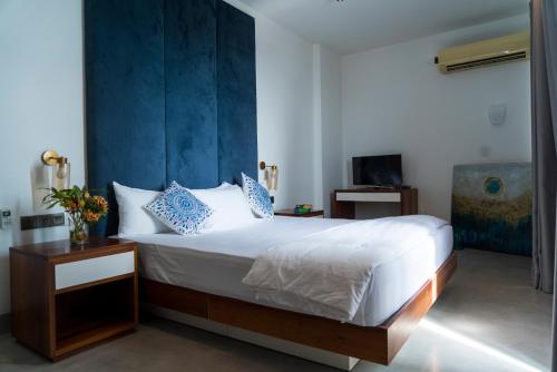 a bedroom with a large bed with a blue headboard at Four Petals Inn in Colombo