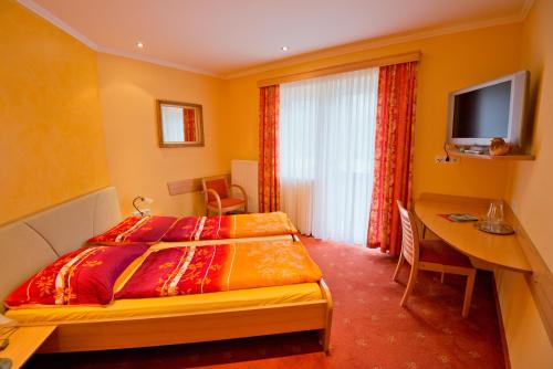 a bedroom with a bed and a desk and a television at Frühstückspension Seeberghof in Seewiesen