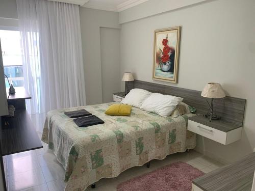 1 dormitorio con cama, lámpara y ventana en Quadra mar perto Roda Gigante, en Balneário Camboriú