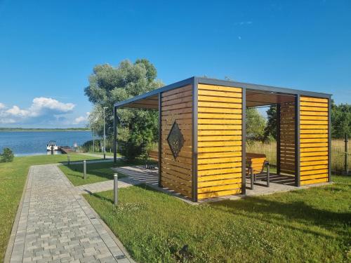 une petite cabane en bois sur l'herbe près de l'eau dans l'établissement Zacisze Mazurskie, à Ryn
