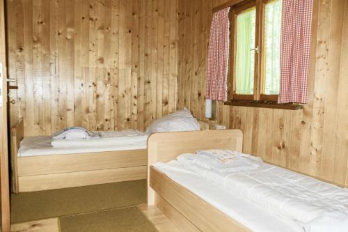 Habitación de madera con 2 camas y ventana en Ferienhaus Schetteregg en Egg