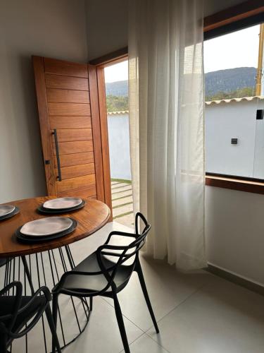 een eetkamer met een tafel en stoelen en een raam bij chalé cantin casa temporada 900 m praça tiradentes in Tiradentes