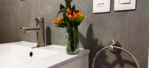 a vase of flowers sitting on top of a sink at Central y Moderno Apto 1 habitación - Lift Gaucho in Montevideo