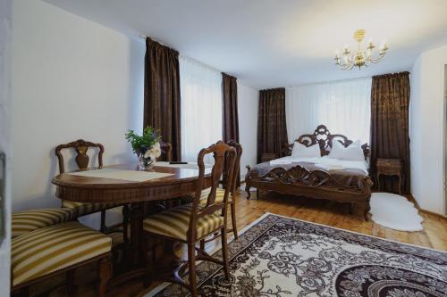 a bedroom with a table and a bed and a table and chairs at CASA BARONULUI in Baia Mare