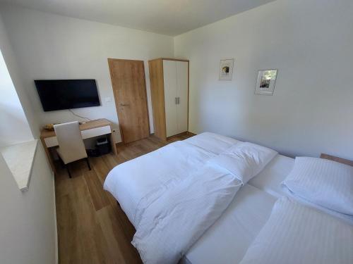 a bedroom with a bed and a desk with a television at Gostilna in pizzeria Pri Brajdi in Komen