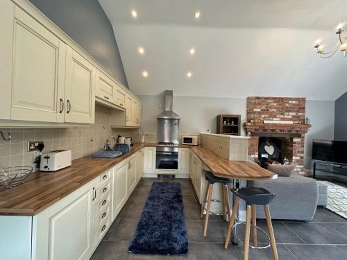 a kitchen with white cabinets and a table and a fireplace at The Red Lodge Annexe in Woodborough