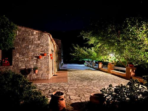a stone walkway with a stone wall and trees at night at Mandra Chiusilla in Collesano