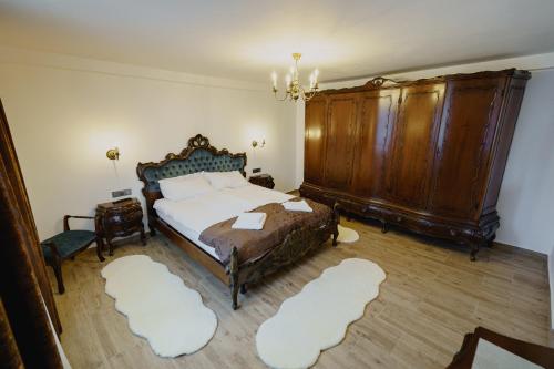 a bedroom with a large bed and a wooden cabinet at CASA BARONULUI in Baia Mare