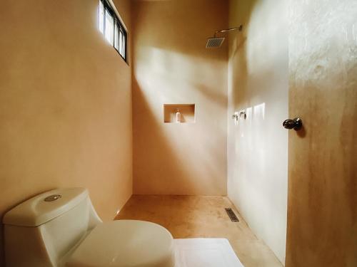 a bathroom with a white toilet and a window at Che Valladolid Hostel & Bar Adults Only in Valladolid