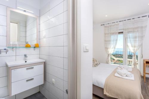 ein Bad mit einem Bett, einem Waschbecken und einem Spiegel in der Unterkunft Apartman Spin in Kastav