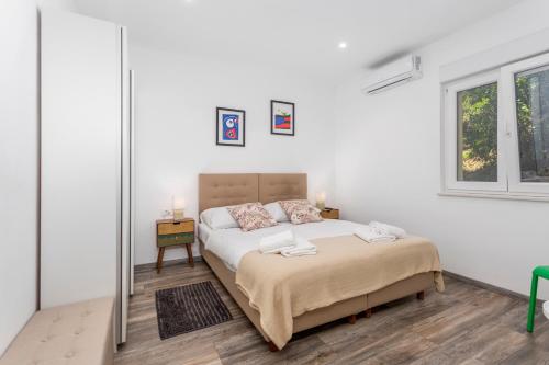a white bedroom with a bed and a window at Apartman Spin in Kastav