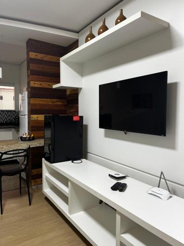 a living room with a white table with a tv on a wall at Apart Hotel Seg Total Lofts Encantadores in Mogi-Guaçu