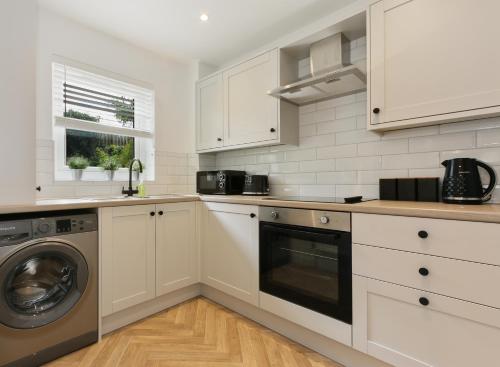 a kitchen with white cabinets and a washer and dryer at City Oaks - Sheffield Station & Utilita Arena in Sheffield