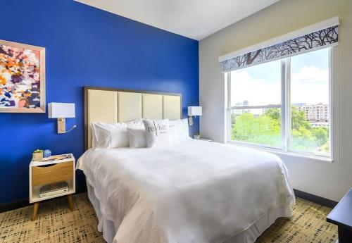 Cama blanca grande en habitación azul con ventana en Private Downtown Apartment With King Bed, en Raleigh