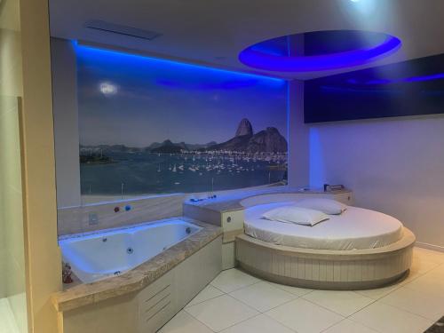 a room with a bath tub with a large window at Passione Criciúma - Adult Only in Criciúma