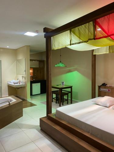 a bedroom with a bed and a kitchen with a table at Passione Criciúma - Adult Only in Criciúma