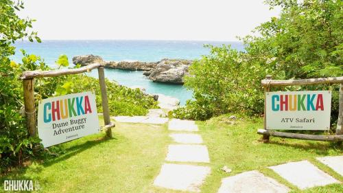 a path leading to the ocean with two signs at OceanAire Crest @ Oceanpointe in Lucea