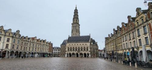 una plaza de la ciudad con una torre de reloj en la distancia en Entre les places, avec Parking Gratuit en Arras