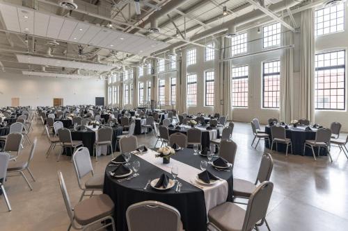 um grande salão de banquetes com mesas e cadeiras em The Warehouse Hotel at Champion Mill em Hamilton
