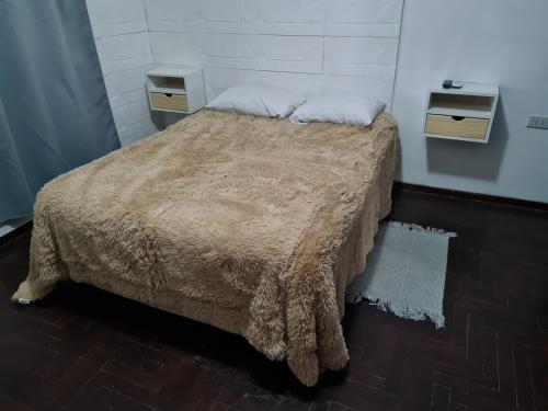 a bedroom with a bed with two night stands and two tables at Casa a minutos del Aeropuerto in Ezeiza