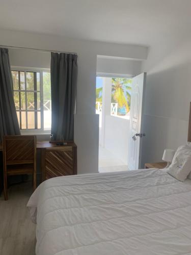 a bedroom with a bed and a desk and a window at Hotel El Quemaito - Luxury Oceanfront Retreat in Santa Cruz de Barahona