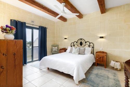 a bedroom with a bed and a ceiling fan at Dar ta' Censina Villa with Private Pool in Għasri