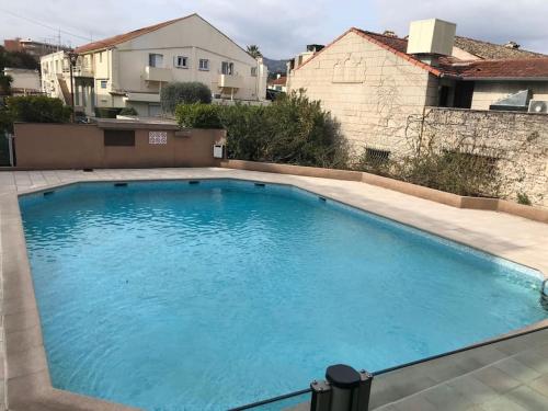 a large swimming pool with blue water in a yard at Perle rare 2 pièces au pied de la plage et piscine résidence in Mandelieu-la-Napoule